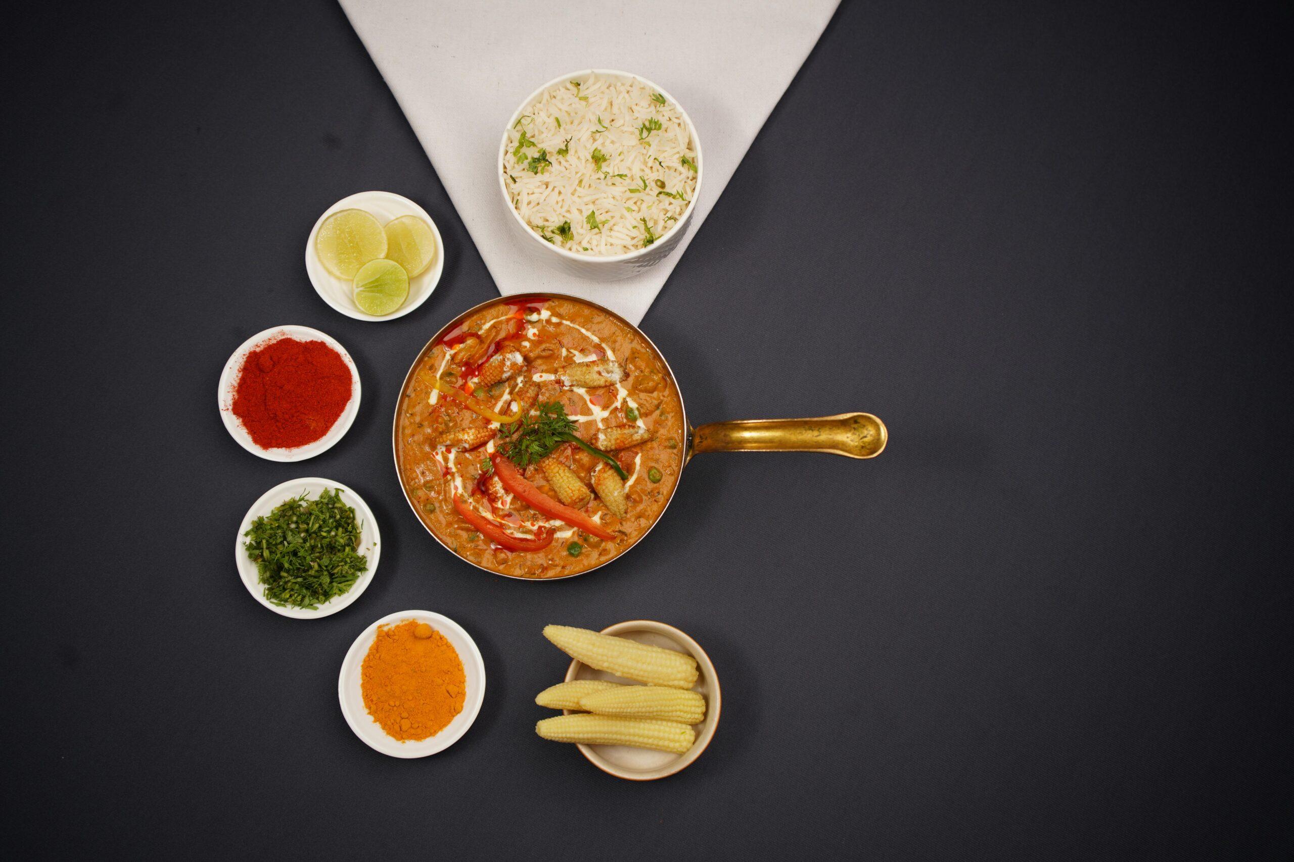Top view of an Indian curry with basmati rice and an array of spices, showcasing authentic flavors.